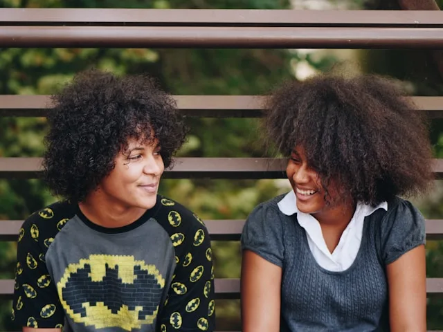 Two black women looking at themselves and smiling